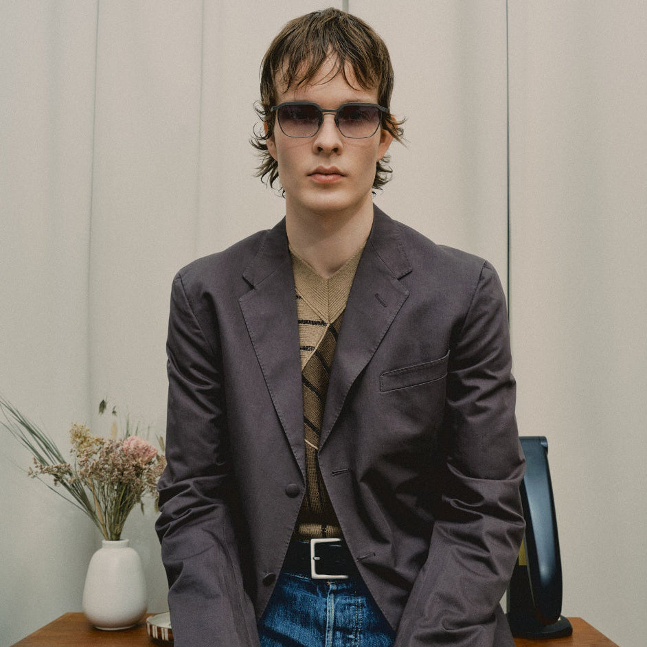 Model in a charcoal blazer and striped sweater wearing Vincent Catani Benno Space Grey Gradient sunglasses