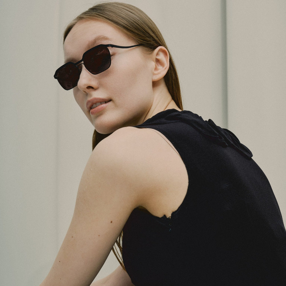 Model in a black top wearing Vincent Catani Benno all-black sunglasses